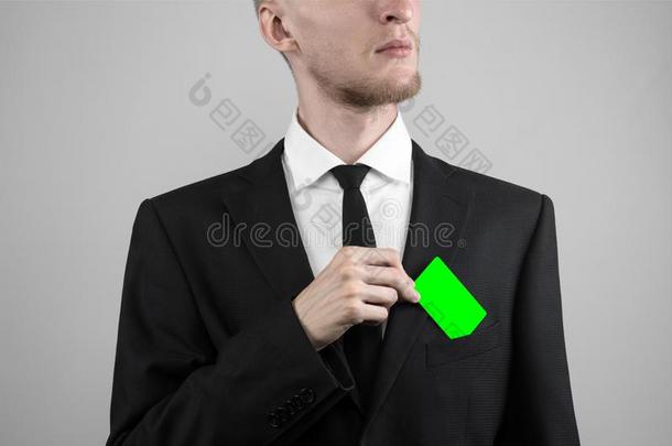 商人穿着黑色西装和黑色领带拿着一张<strong>卡片</strong>，一只手拿着一张<strong>卡片</strong>，绿卡，<strong>卡片</strong>被插入，绿色的色度