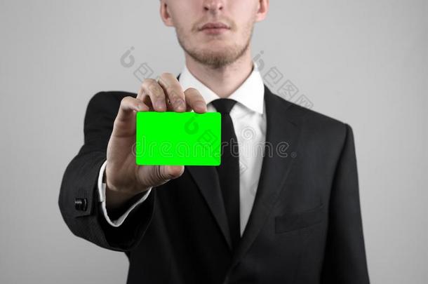 商人穿着黑色西装和黑色领带拿着一张卡片，一只手拿着一张卡片，绿卡，卡片被插入，绿色的色度