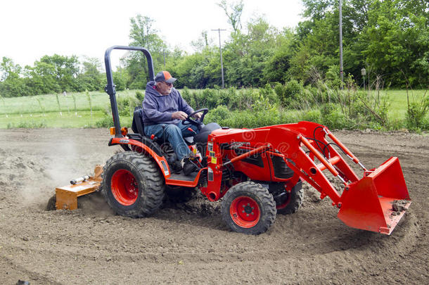 年迈的农民用一台紧凑型4x4拖拉机在他的花园里耕作