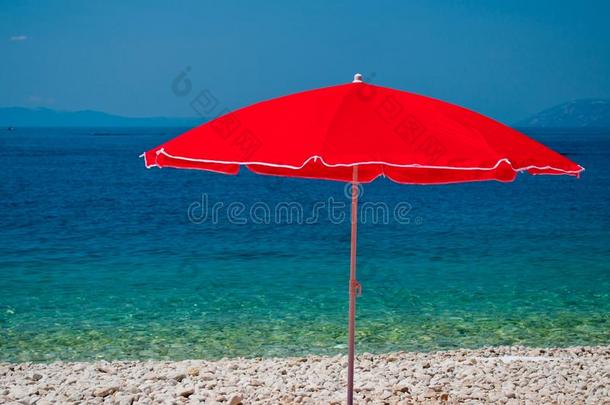 夏天有鹅卵石和红色遮阳伞的海滩