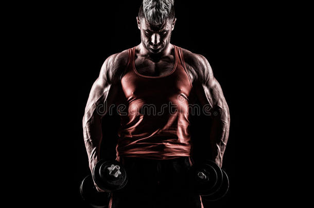 一个肌肉发达的年轻人在黑暗的背景下举重的特写