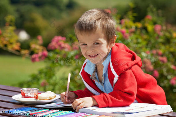 可爱的小男孩穿着红毛衣，在书上画画