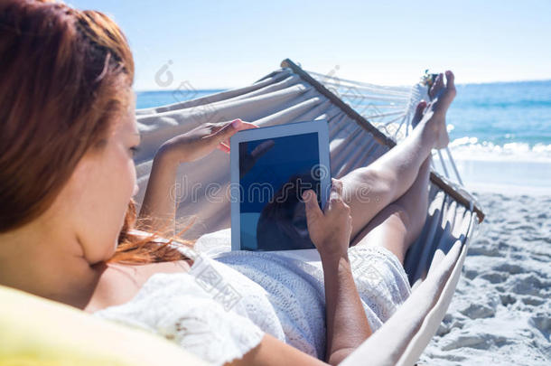 黑发女人在吊床上放松时使用平板电脑