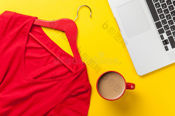 杯子和笔记本电脑靠近红色连衣裙