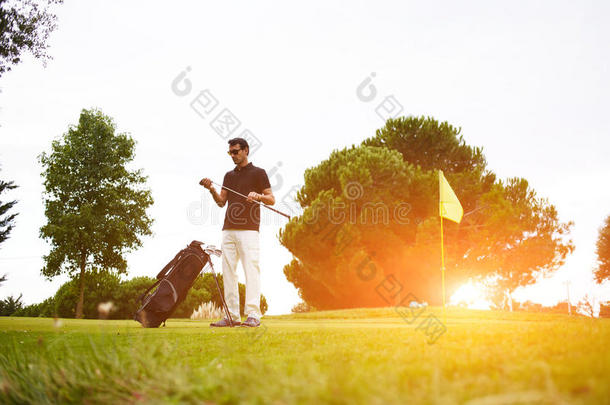 一个男人在时尚的马球上富有自信，花时间打高尔夫。 专业高尔夫球手在撞击前擦一根棍子