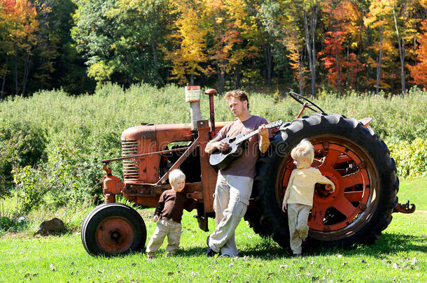 父亲和儿子们用旧农场拖拉机弹吉他