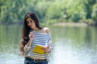 在河边公园里拿着笔记本的女孩图片