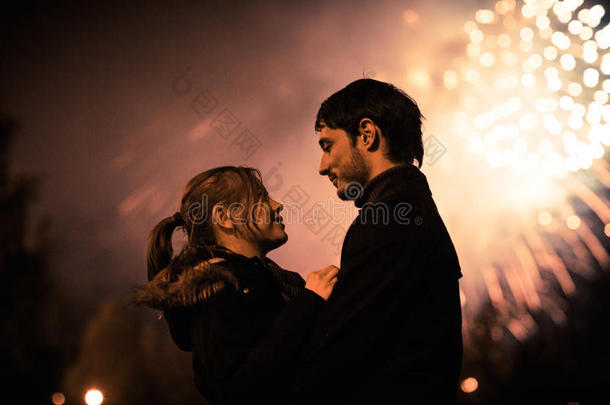 一对接吻夫妇在一个巨大的烟花表演前的剪影。