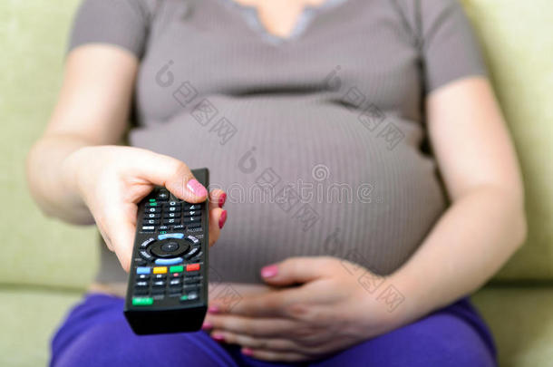 孕妇手持遥控器的特写图像
