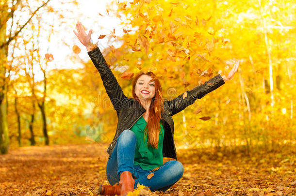 秋天公园里放松的女孩把树叶抛向空中。