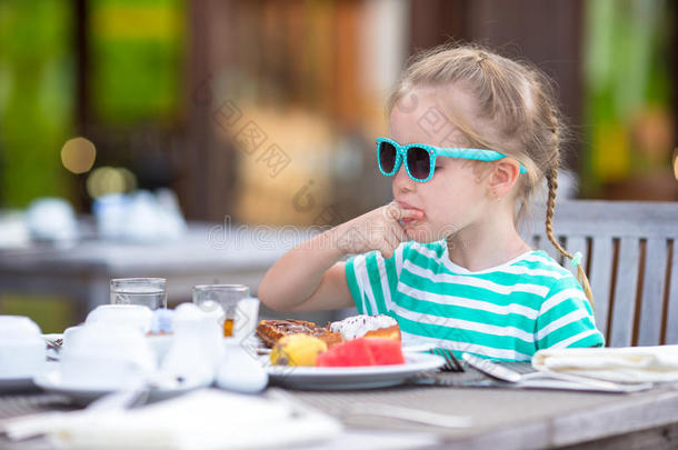 可爱的小女孩在户外吃早餐