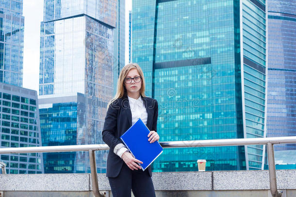 <strong>商务</strong>妇女拿着文件夹，手里拿着文件，背景是摩天大楼