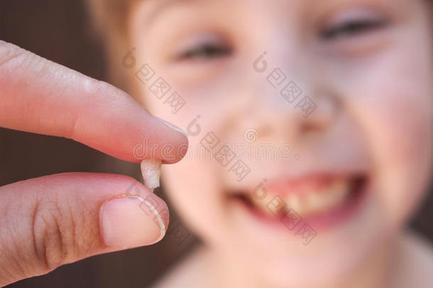 在6岁的孩子失去了婴儿的牙齿。 那个女孩手里拿着牙齿