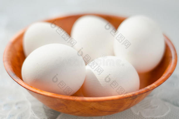 鸡蛋放在白色桌子上的木碗里