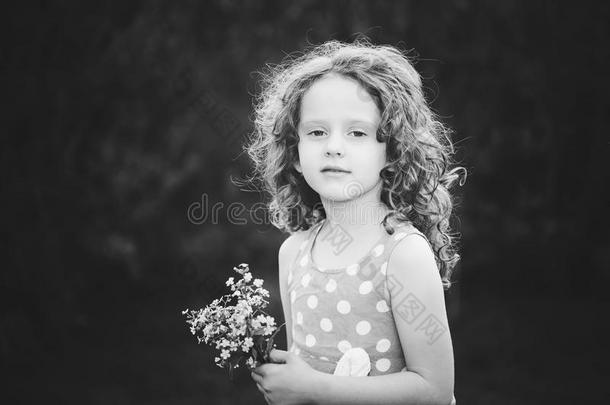漂亮的小女孩手里拿着一朵花。 黑白相间