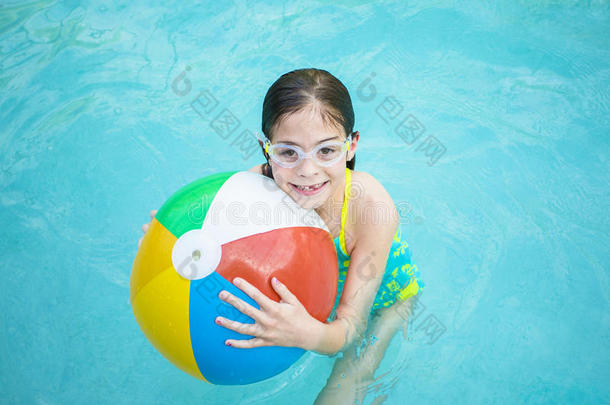 可爱的小女孩在游泳池里玩沙滩球