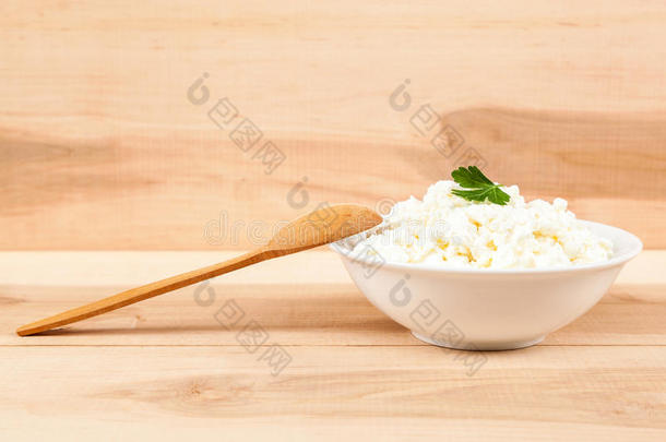 <strong>用勺子</strong>放在白色碗里的新鲜干酪。