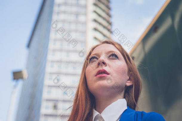 美丽的红头发女孩在城市背景下摆姿势