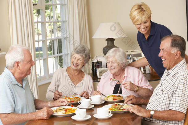 一群年长的夫妇在家里的帮助下一起在<strong>养老院</strong>里享受晚餐