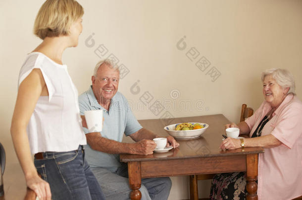 成年女儿在厨房和年长的父母分享一杯茶