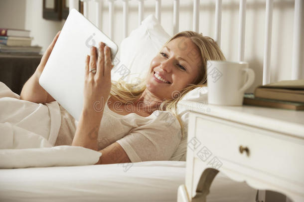 在家里躺在床上用数字平板电脑的女人