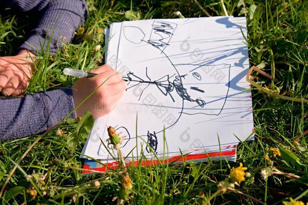 近景<strong>儿童手绘</strong>彩色装饰品在纸上。 笔记本在草地的新鲜青草中。