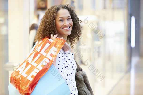 兴奋的女购物者拿着购物袋在商场里购物