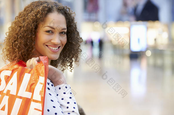 兴奋的女购物者拿着购物袋在商场里购物