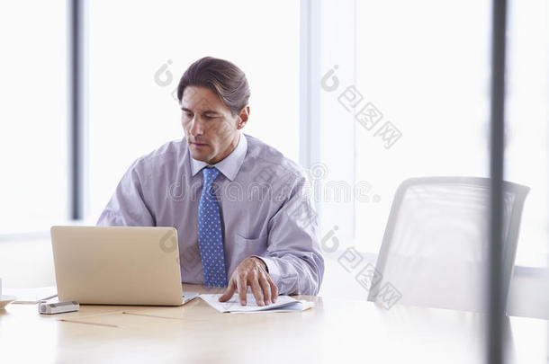 商人在会议室桌子上做笔记本电脑
