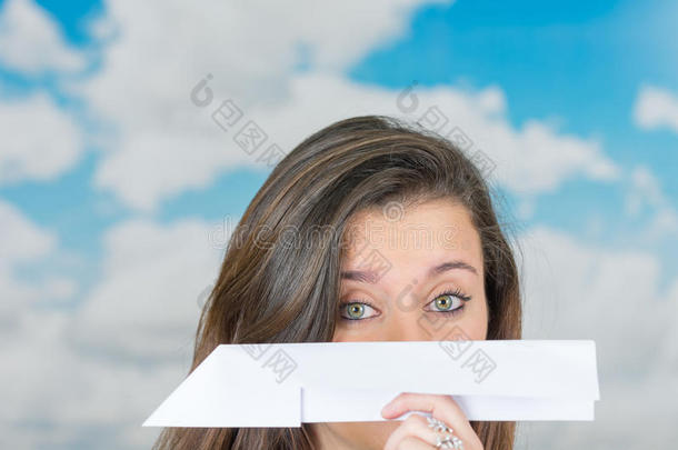 黑发女人拿着一架纸飞机在云前