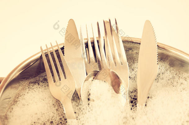 关闭厨房里洗过的盘子：银匙，叉子和刀。 复古过滤图像