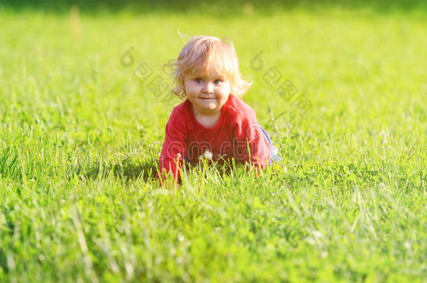 可爱的小女孩在夏天的草坪上学习爬行