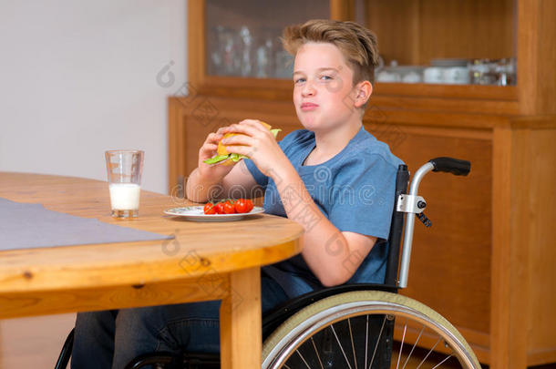 坐轮椅的残疾男孩正在吃饭