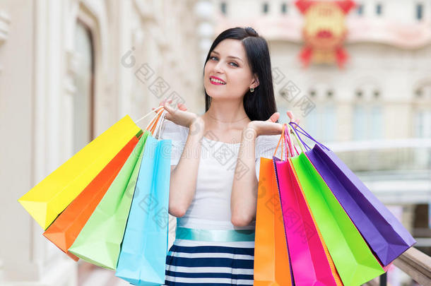 一个快乐的微笑的女士，有很多五颜六色的购物袋，从高档商店。