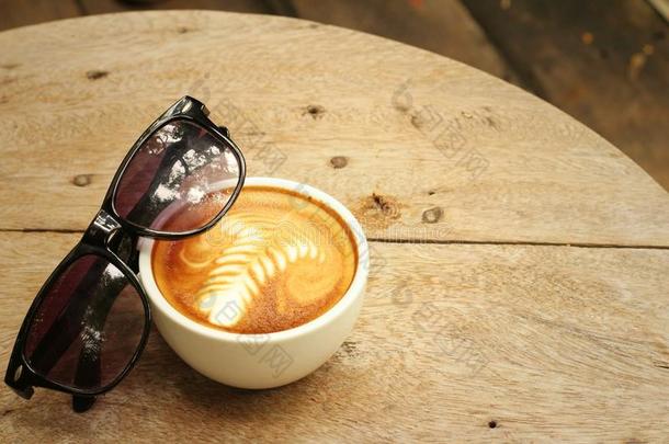 木制背景上带太阳眼镜的咖啡。