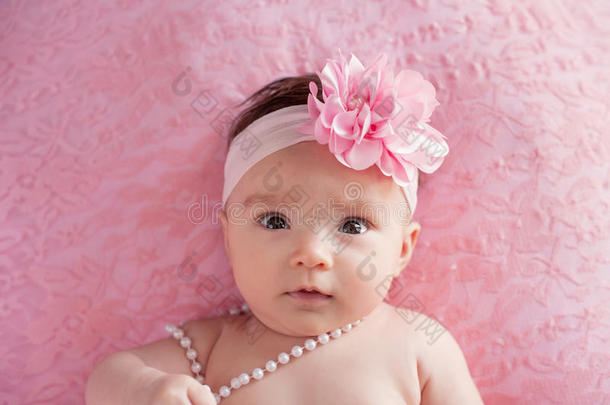 小女孩有一个大的，粉红色的，花头带和珍珠