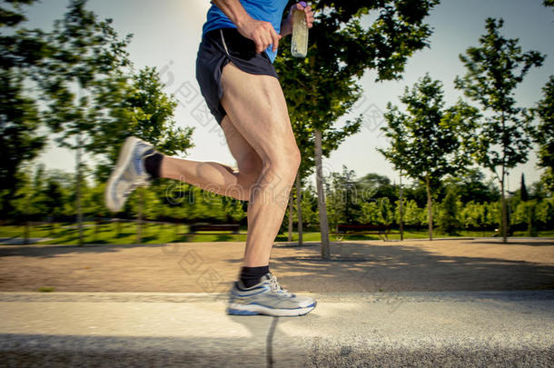 夏季训练期间，在城市公园与树木<strong>一起跑</strong>步的年轻人的运动腿练习运动健康的生活方式