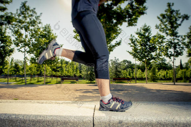 关闭年轻人在城市公园跑步的腿，在夏季训练课上用树木练习运动健康的生活方式概念
