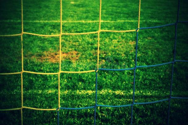详细的黄色蓝色交叉<strong>足球</strong>网，<strong>足球</strong>在<strong>球门</strong>网与绿草在操场的背景。