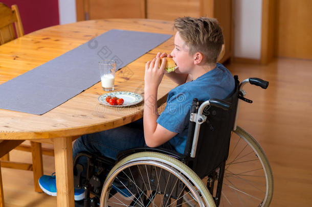 坐轮椅的残疾男孩正在吃饭