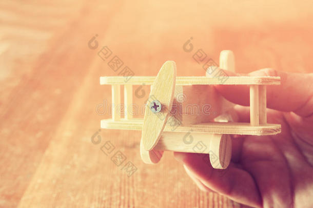 特写照片，男人的手拿着木制玩具飞机在木制背景上。 过滤后的图像。 愿望和简单的概念