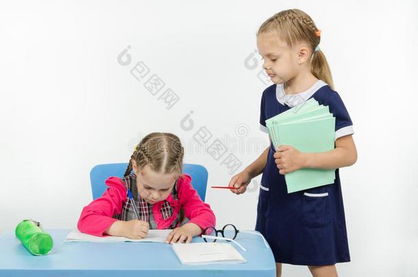 女孩老师站在学生桌旁