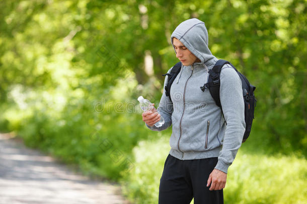 活跃的人拿着一瓶水，户外。 年轻的肌肉男会止渴