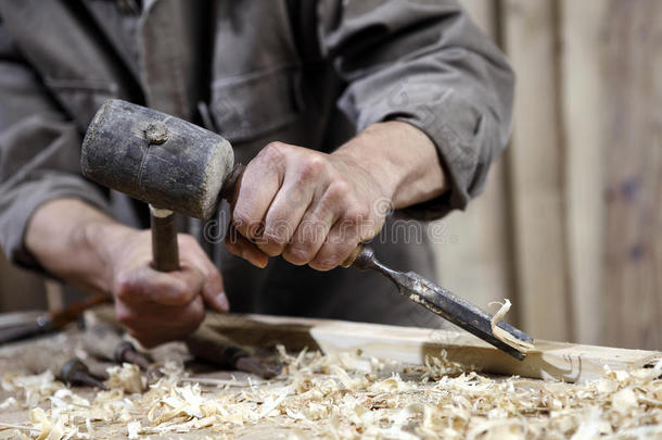 <strong>木工用</strong>锤子和凿子在工作台上的木匠的手