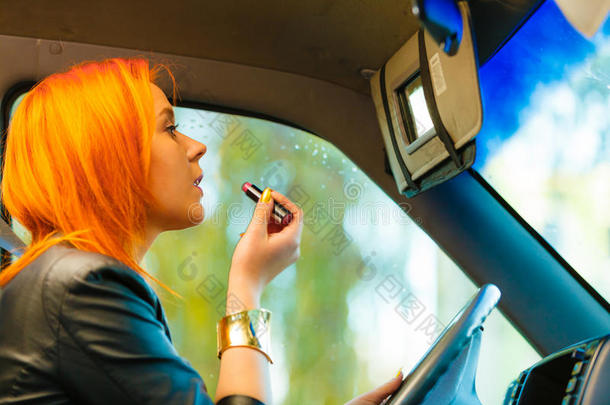 一个女孩开车时画嘴唇化妆。