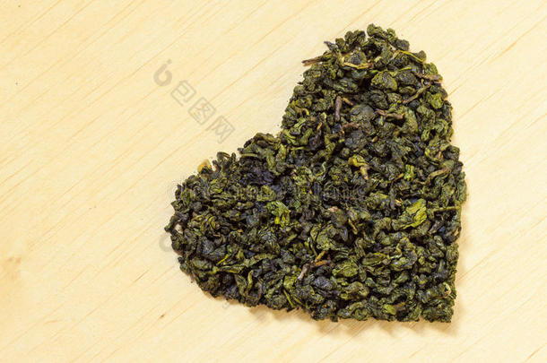 木质表面上的心形绿茶叶