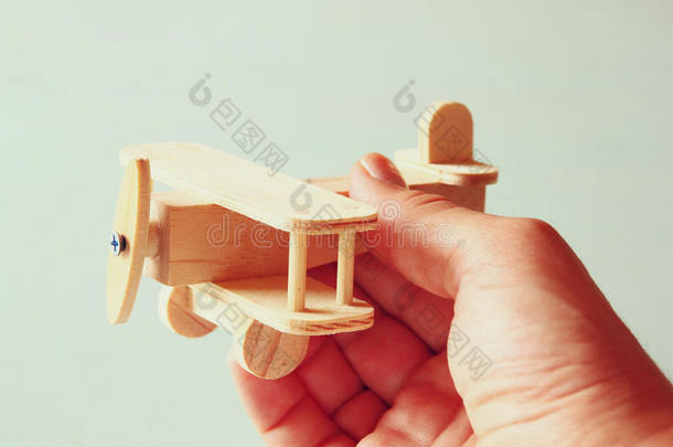 特写照片，男人的手拿着木制玩具飞机在木制背景上。 过滤后的图像。 愿望和简单的概念