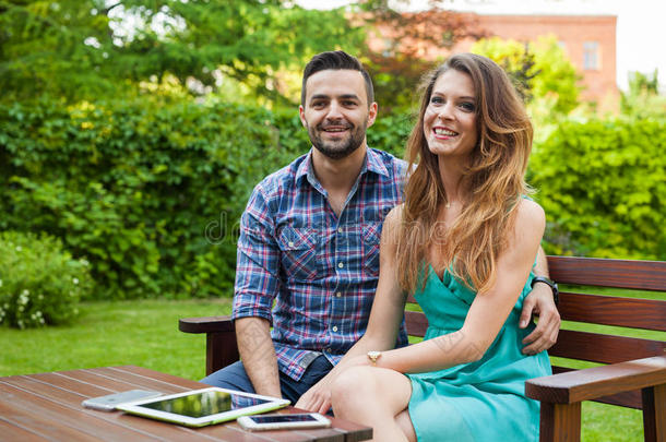 一对夫妇坐在花园里的长凳上自拍。