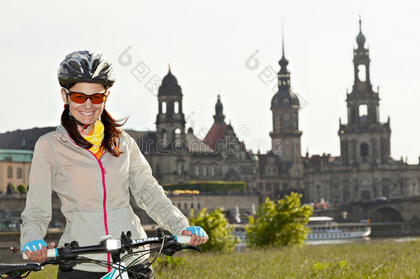 成年迷人的女自行车手在背景下摆姿势