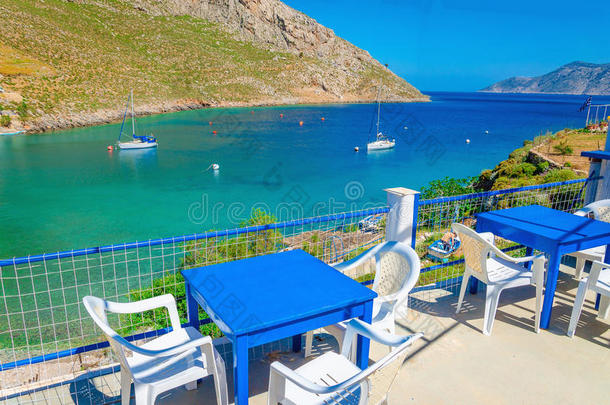 希腊岛海湾的蓝色木制桌椅